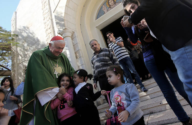 Cardinal Vincent Nichols of Westminster, England, greets children after celebrating Mass. (CNS photo/Mohammed Saber, EPA)