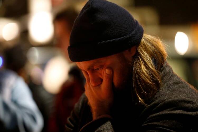 A mourner pauses Dec. 5 at a makeshift memorial near the scene of a fatal warehouse fire in Oakland, Calif. The Dec. 2 blaze claimed the lives of at least 33 people. (CNS photo/Stephen Lam, Reuters)