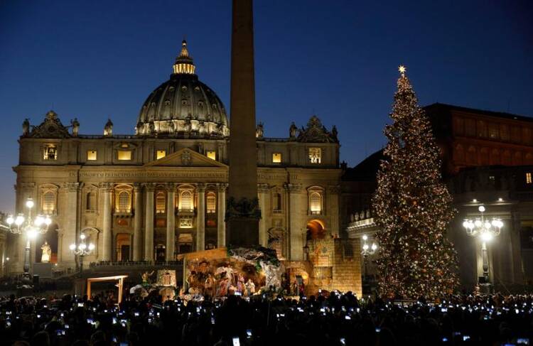 People take photos on their mobile devices as the Christmas tree is lit during a ceremony in St. Peter's Square at the Vatican on Dec. 9. (CNS photo/Paul Haring)