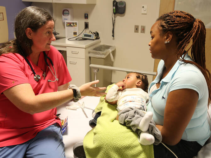 Mercy Sister Karen Schneider, who is a pediatrician, talks with the mother of a child in the emergency room at Johns Hopkins Hospital in Baltimore in 2014. U.S. health care seemed stuck in the waiting room for part of the year, holding out for its future prognosis from courtroom and political decisions. (CNS photo/Bob Roller) 