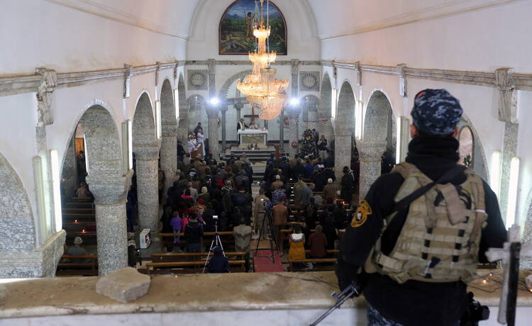 An Iraqi policeman stands guard as worshippers pray during Christmas Eve Mass in 2016 at al-Tahira al-Kubra church in Mosul. (CNS photo/Mohammed Badra, EPA)