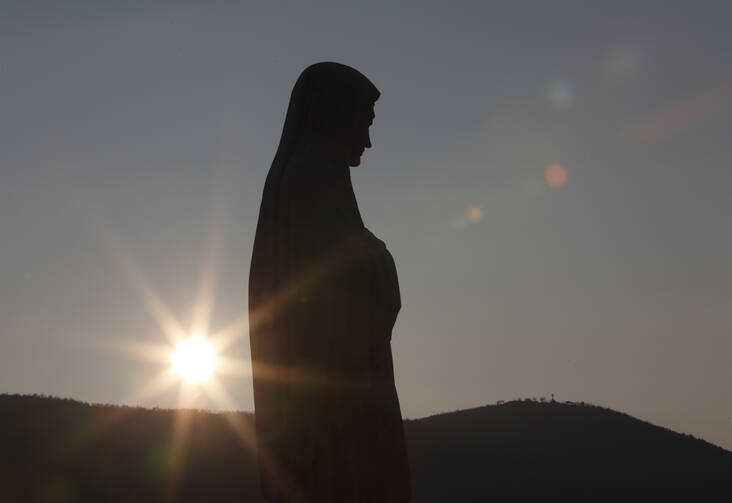 The sun sets behind a statue of Mary on Apparition Hill in Medjugorje, Bosnia-Herzegovina. (CNS photo/Paul Haring)