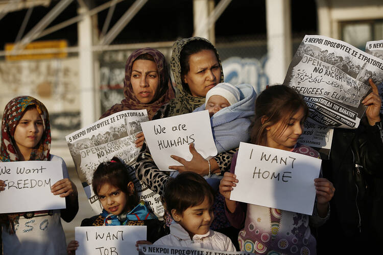 Afghan women hold placards as they take part in a protest demanding better living conditions at the refugee camp of the former international Helliniko airport in Athens, Greece, on Feb. 18. (CNS photo/Yannis Kolesidis, EPA)