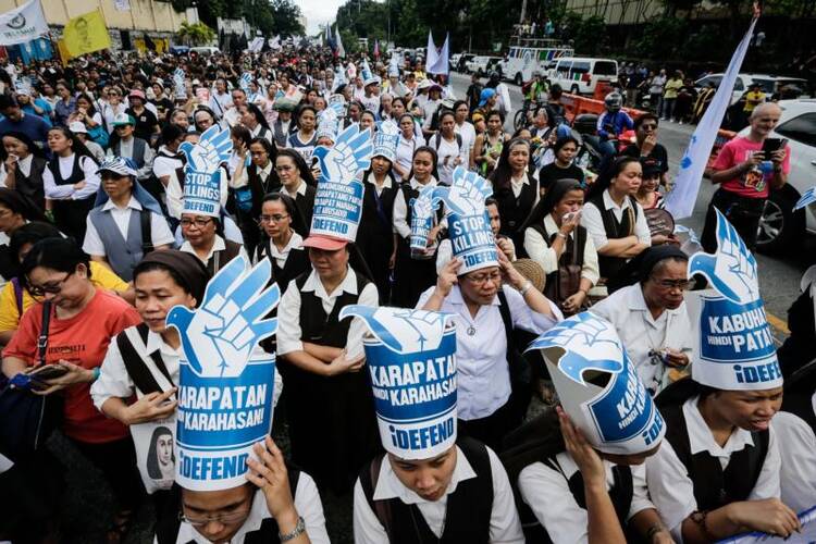 Filipino nuns wearing hats with messages against human rights violations join a Feb. 25 demonstration to mark the 31st anniversary of the People Power revolution in Manila. (CNS photo/Mark R. Cristino, EPA)