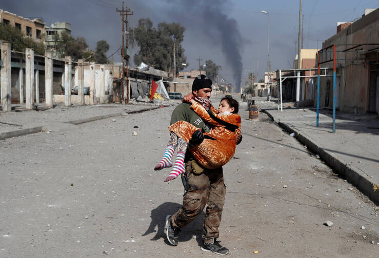 An Iraqi soldier carries an injured woman during a battle with the Islamic State group in Mosul on Feb. 28. Iraqi troops were engaged in difficult fighting with Islamic State forces in northern Iraq in an effort to reclaim land held by the militant group.(CNS photo/Goran Tomasevic, Reuters)