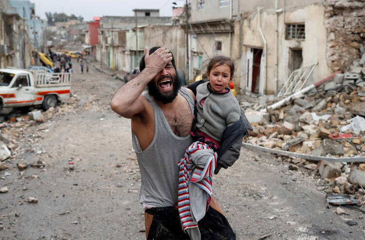 A man weeps as he carries his daughter away from an Islamic State-controlled part of Mosul toward Iraqi special forces soldiers during a battle on March 4. (CNS photo/Goran Tomasevic, Reuters)