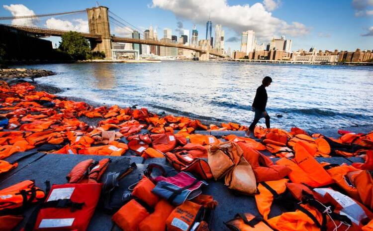 A woman in New York walks past hundreds of refugee life jackets collected from the beaches of Greece on Sept. 16, 2016. (CNS photo/Justin Lane, EPA)