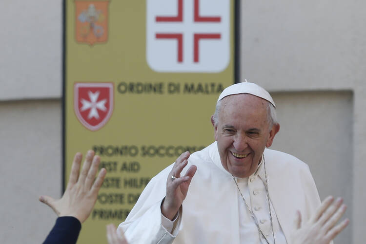 Pope Francis passes a sign placed by the Order of Malta as he greets the crowd during his general audience in St. Peter's Square at the Vatican on April 5. (CNS photo/Paul Haring) 