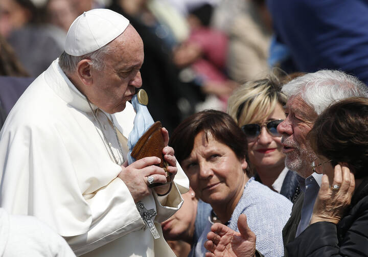 Pope Francis kisses a Marian statue presented by someone in the crowd during his general audience in St. Peter's Square at the Vatican on April 5. (CNS photo/Paul Haring)