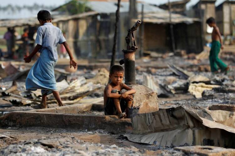 A boy sits amid debris after a 2016 fire destroyed shelters at a camp for people displaced by violence in Sittwe, Myanmar. (CNS photo/Soe Zeya Tun, EPA)