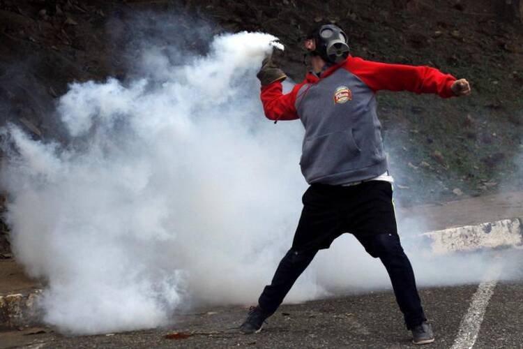 A demonstrator throws a tear gas canister back at police during an April 5 protest in San Cristobal, Venezuela. (CNS photo/Carlos Eduardo Ramirez, Reuters)