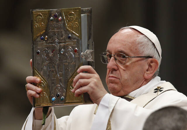 Pope Francis raises the Book of the Gospels as he celebrates Holy Thursday chrism Mass in St. Peter’s Basilica at the Vatican April 13. 