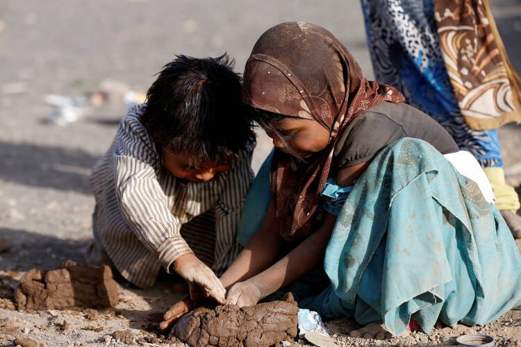 Children play with mud on April 24 at a camp for people displaced by violence near Sanaa, Yemen. (CNS photo/Khaled Abdullah, Reuters)