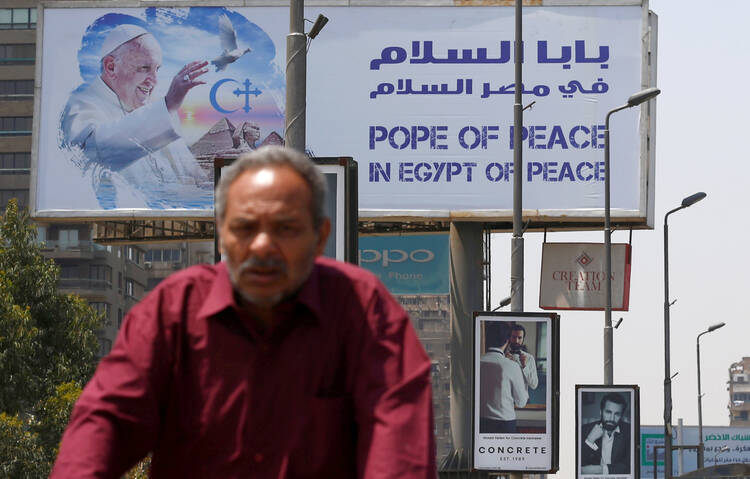 A man rides a bicycle past a billboard with an image of Pope Francis April 26 ahead of the pontiff's April 28-29 visit to Cairo. (CNS photo/Amr Abdallah Dalsh, Reuters)