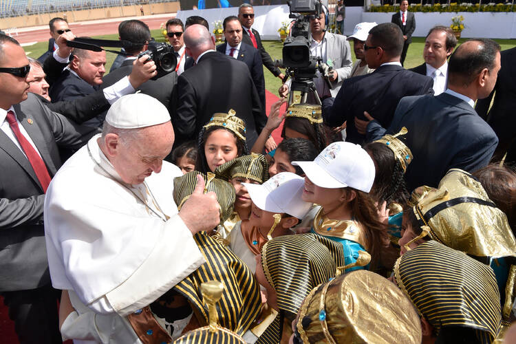 Pope Francis greets children dressed as pharaohs and in traditional dress as he arrives to celebrate Mass at the Air Defense Stadium in Cairo April 29. (CNS photo/L'Osservatore Romano)