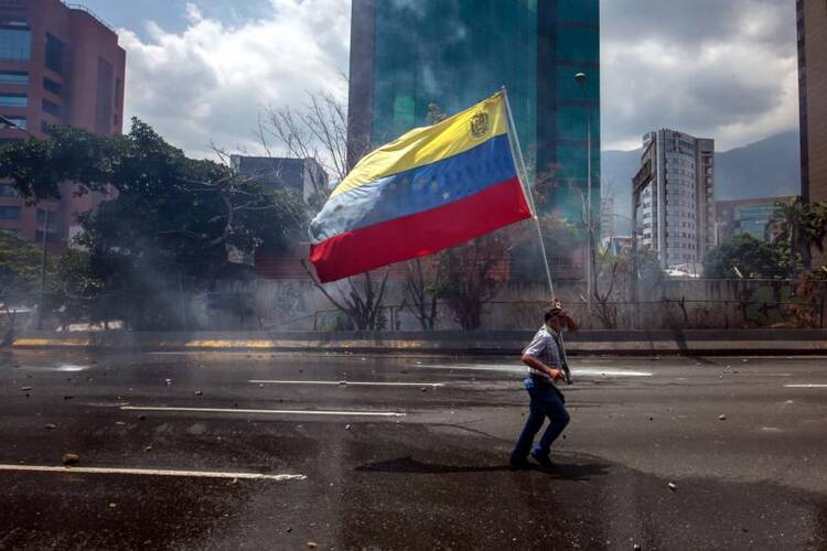 A demonstrator carries VenezuelaÕs flag in Caracas, Venezuela, on April 26. (CNS photo/Miguel Gutierrez, EPA)