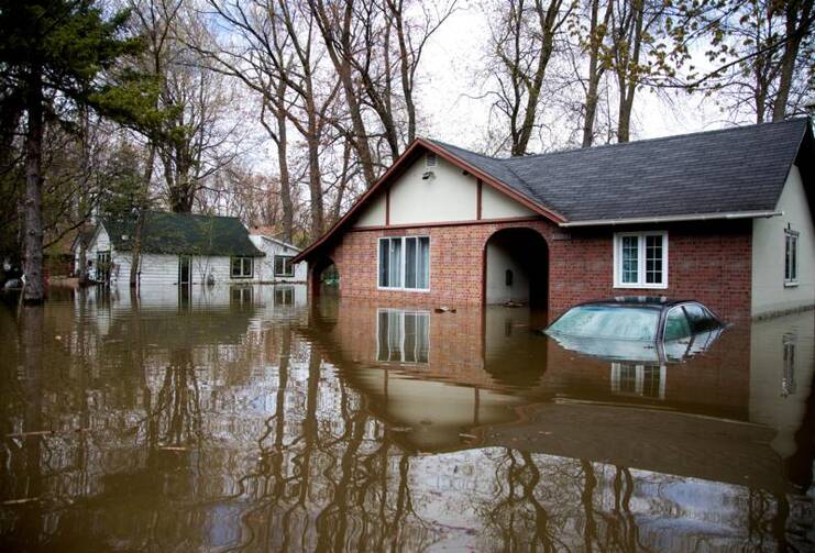 A car is seen submerged in front of a home on May 9 in the flooded Montreal suburb of Pierrefonds, Quebec. A mix of heavy rains and melting snow caused the situation. (CNS photo/Christinne Muschi, Reuters)