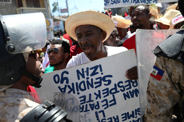 A man argues with a Haitian National Police officer on March 1 as a police line blocks a street during a march calling for better labor conditions in Port-au-Prince. (CNS photo/Andres Martinez Casares, Reuters) 