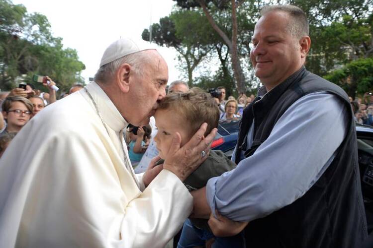 Pope Francis kisses a child during a visit to give an Easter blessing to homes in a public housing complex in Ostia, a Rome suburb on the Mediterranean Sea, on May 19. (CNS photo/L'Osservatore Romano)