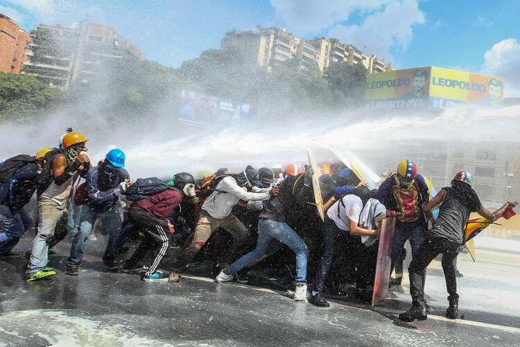 Government protestors in Caracas, Venezuela, are sprayed by a national guard water canon May 29. (CNS photo/Mauricio Duenas, EPA)