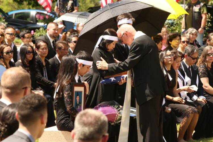 Msgr. Richard Paperini comforts Myhanh Best, wife of Ricky Best, who was killed on a Portland, Ore., commuter train on May 26 while defending two girls from an anti-Muslim racist attack. (CNS photo/Ed Langlois, Catholic Sentinel)