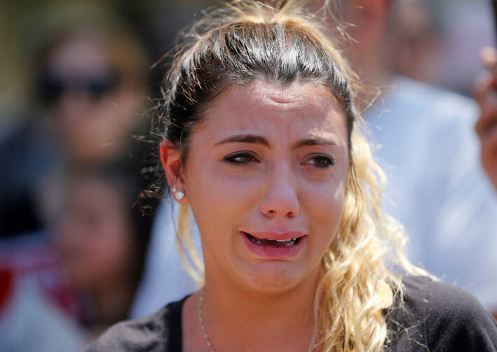 Chaldean-American Lavrena Kenawa cries during a June 12 rally outside the Mother of God Chaldean Catholic Church in Southfield, Mich. Her uncle was among dozens of Chaldean Christians who were arrested by federal immigration officials over the weekend of June 10 and 11 in the Detroit metropolitan area, which members of the local church community said left them sad and frustrated. (CNS photo/Rebecca Cook, Reuters)