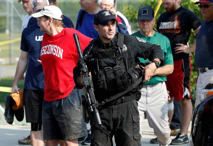 A U.S. Capitol police SWAT team officer escorts members of Congress and congressional staff from the scene after a gunman opened fire on Republican members of Congress during a baseball practice in Alexandria, Va., on June 14. (CNS photo/Joshua Roberts, Reuters)