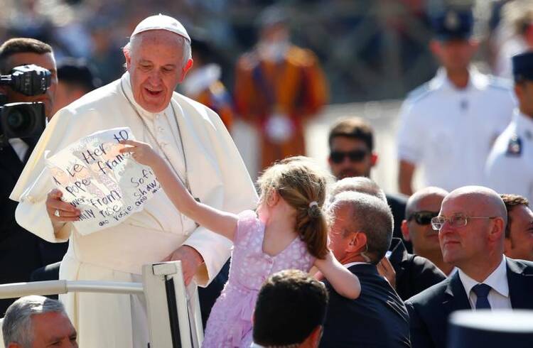 Pope Francis receives a letter from a girl as he arrives for his general audience on June 21 in St. Peter's Square at the Vatican. (CNS photo/Tony Gentile, Reuters)