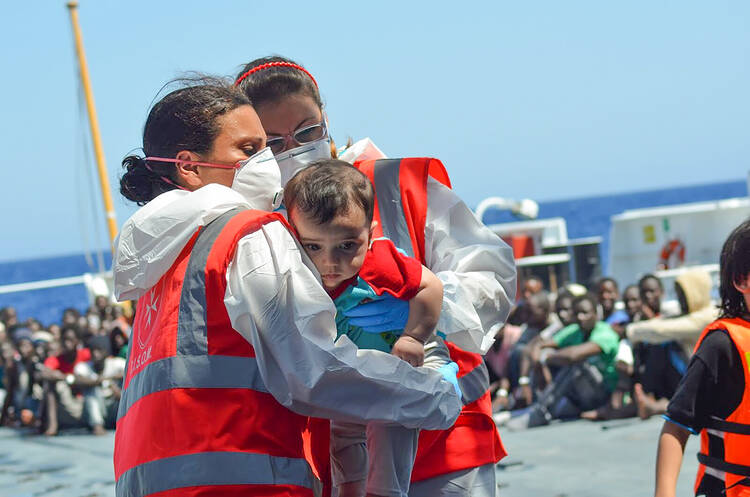 Volunteers of the Order of Malta's Italian Relief Corps provide assistant to an infant rescued in the Mediterranean Sea. (CNS photo/courtesy CISOM) 