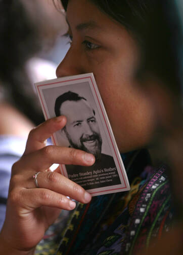 A woman holds a booklet with a picture of Father Stanley Rother