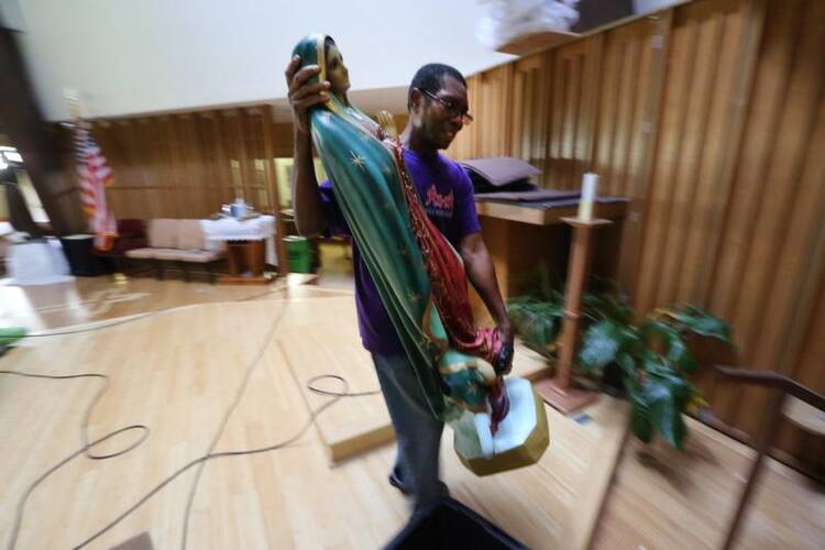 Father Martin Eke, pastor of St. Francis of Assisi Church in Houston, recovers a statue of Our Lady of Guadalupe on Sept. 6 that was severely damaged from the floodwaters of Tropical Storm Harvey. The parish is home to a large African-American community in the Archdiocese of Galveston-Houston. (CNS photo/Bob Roller)