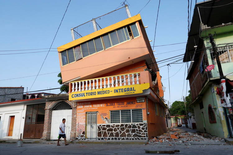 A man walks next to an earthquake-damaged building in Juchitan, Mexico, on Sept. 9. (CNS photo/Carlos Jasso, Reuters)