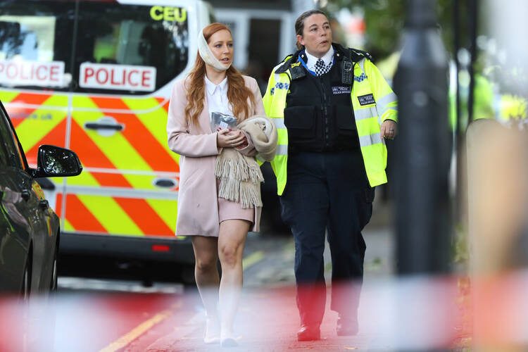 An injured woman is led away following a blast caused by an improvised explosive device on a London Underground train Sept. 15. The blast injured more than a dozen people and is being treated as terrorism by police investigators. (CNS photo/Luke MacGregor, Reuters)