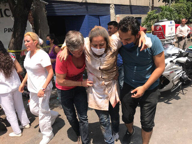 An injured woman is assisted in Mexico City on Sept. 19 after a magnitude 7.1 earthquake hit to the southeast of the city, killing hundreds. (CNS photo/Carlos Jasso, Reuters)