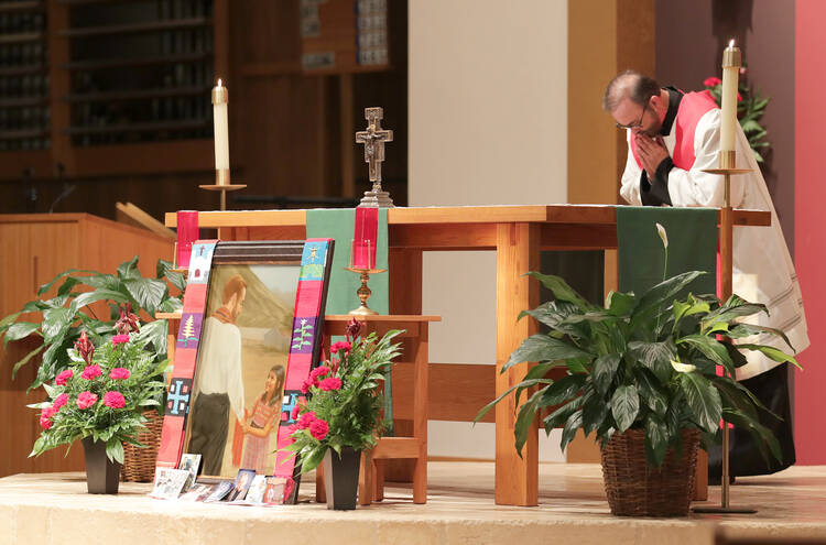 Father Joe Townsend, pastor of St. Benedict Parish in Broken Arrow, Okla., bows before the altar and an image of Father Stanley Rother during a Sept. 22 vespers and vigil