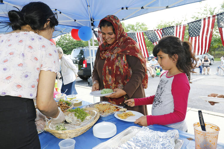 A Pakistani woman and her daughter stand in a buffet line during a Catholic Charities-hosted party for refugees held in observance of World Refugee Day June 2017 in Amityville, N.Y. (CNS photo/Gregory A. Shemitz)