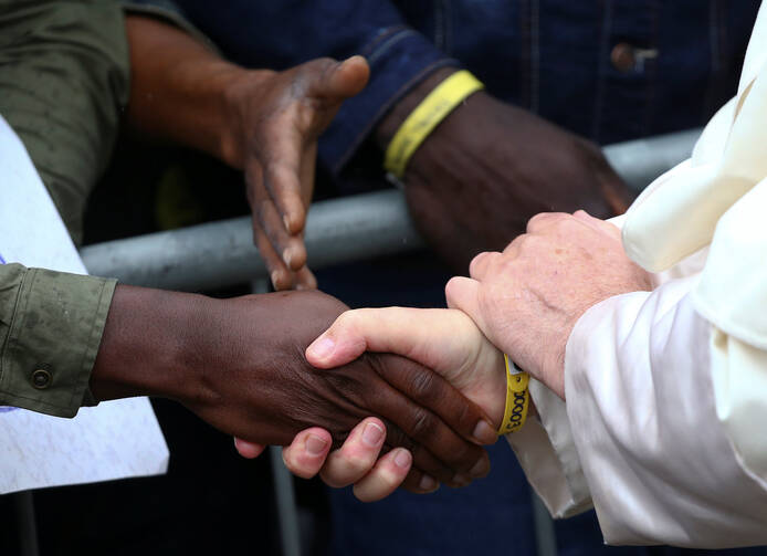 Pope Francis shakes hands with a man as he visits a migrant reception centre during a pastoral visit in Bologna, Italy, Oct. 1. The pope is seen wearing a yellow ID bracelet with his name and a number, just like the immigrants and refugees at the center. (CNS photo/Alessandro Bianchi, Reuters)