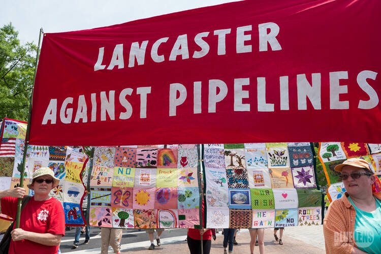 Activists with the Lancaster Against Pipelines carry a banner in late April during the People's Climate March in Washington. Nearly two dozen people were arrested Oct. 16 as they blocked workers from starting construction of a short leg of a natural gas pipeline on property owned by the Adorers of the Blood of Christ in Columbia, Pa. (CNS photo/Mark Dixon, Wikimedia Commons)