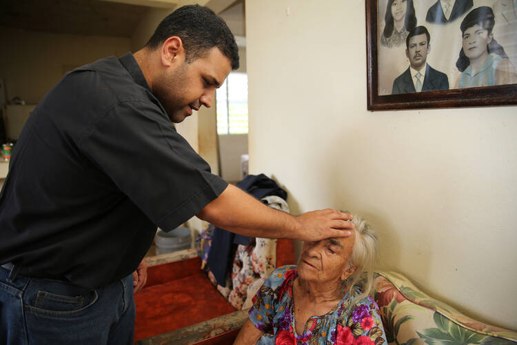 Father Carlos Francis Mendez, pastor of Immaculate Heart of Mary Church in Las Marias, Puerto Rico, blesses Luz Lamboy, 82, who has Alzheimer's and lives alone, at her home in a remote area outside the town Oct. 24. Father Mendez and parishioners distributed relief goods to her home and others in the poor area outside the town who were affected by Hurricane Maria. (CNS photo/Bob Roller)