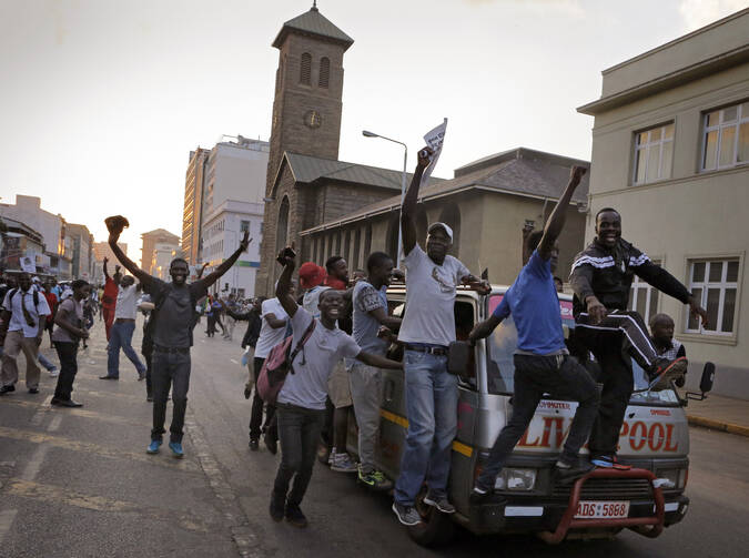 People celebrate Nov. 21 outside parliament after hearing that President Robert Mugabe resigned in Harare, Zimbabwe. All Zimbabweans should have a voice in the country's governance following Mugabe's 37-year presidency, and the new government should embrace diversity, Zimbabwe's bishops said. (CNS photo/Kim Ludbrook, EPA)