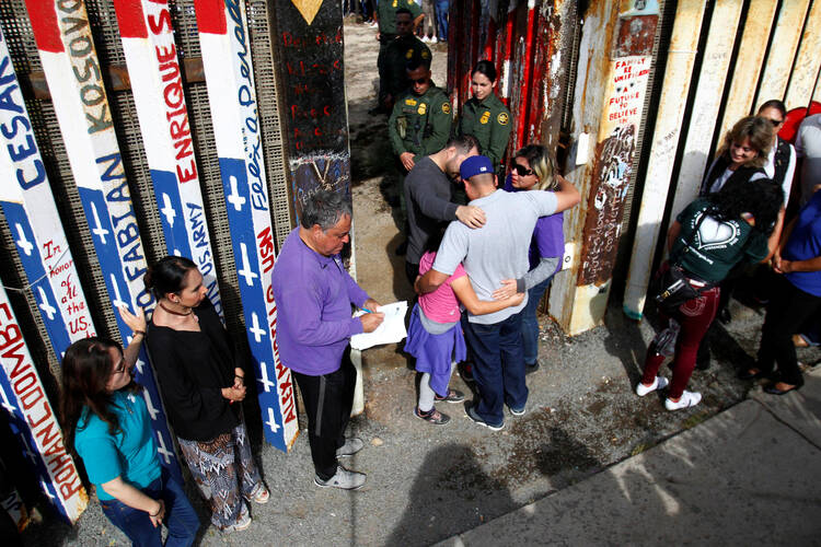U.S. Border Patrol agents open a single gate to allow families to hug and talk on Nov. 18 along the U.S.-Mexico border in Tijuana, Mexico. (CNS photo/Jorge Duenes, Reuters)