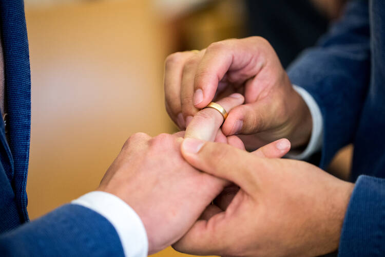 Two same-sex partners exchange wedding bands during a 2017 ceremony at the civil registry office in Munich. (CNS photo/Marc Mueller, EPA)