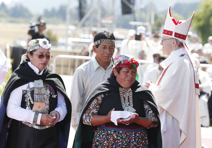 Indigenous people walk past Pope Francis after presenting offertory gifts during the pope's celebration of Mass at the Maquehue Airport near Temuco, Chile, Jan. 17. (CNS photo/Paul Haring)