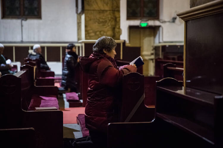 A woman prays during morning Mass on Jan. 30 in the Cathedral of the Immaculate Conception in Beijing. (CNS photo/Roman Pilipey, EPA)