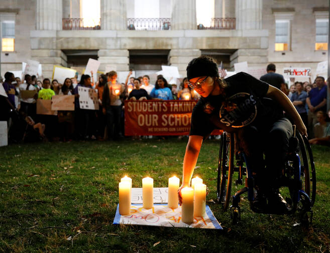 A student lights a candle in front of the North Carolina Capitol in Raleigh on Feb. 20 in memory of the victims of the shooting at Marjory Stoneman Douglas High School in Parkland, Fla. The students were calling for safer gun laws after 17 people were killed when 19-year-old former student Nikolas Cruz stormed the Parkland school on Feb. 14 with an AR-15 semi-automatic style weapon. (CNS photo/Jonathan Drake, Reuters)