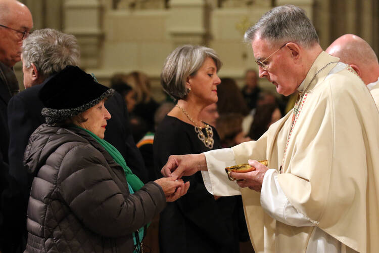 Retired New York Auxiliary Bishop Gerald T. Walsh distributes Communion during a Mass on the March 17 feast of St. Patrick, patron of the Archdiocese of New York, at St. Patrick's Cathedral in New York City. (CNS photo/Gregory A. Shemitz)