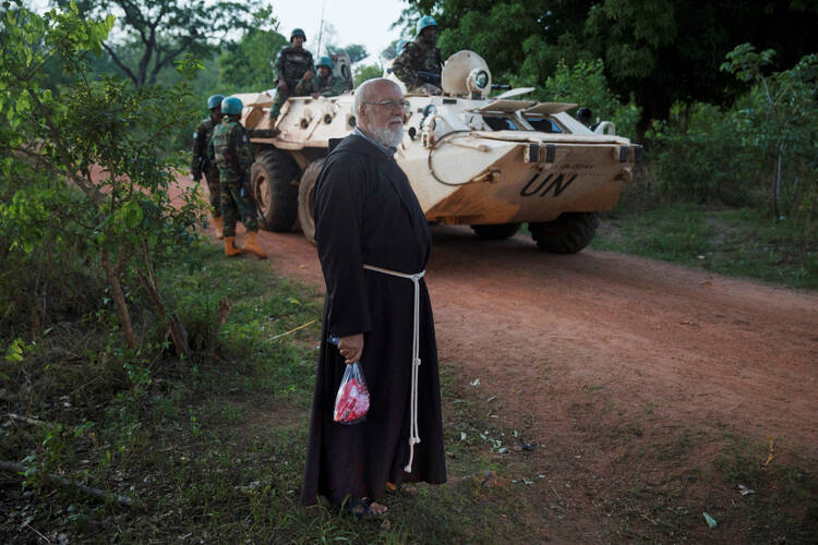 A Franciscan stands near U.N. peacekeeping soldiers in 2017 in the village of Ndim, Central African Republic. The recent death of a Catholic priest in the Central African Republic demonstrates the delicate nature of peace in the country, where a cardinal and an imam have worked to bring the population toward peace and unity. (CNS photo/Baz Ratner, Reuters)