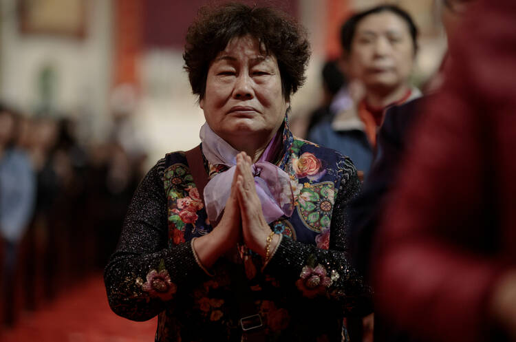  A woman prays during Holy Thursday Mass March 29 at the Cathedral of the Immaculate Conception in Beijing. (CNS photo/Damir Sagolj, Reuters)