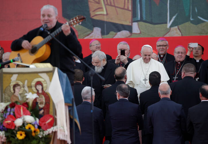 Pope Francis greets people during a gathering of the Neocatechumenal Way at Tor Vergata, a field on the edge of Rome, on May 5. Some 100,000 members of the movement welcomed the pope as they celebrated the 50th anniversary of the movement. Also pictured is Kiko Arguello, co-founder of the Neocatechumenal Way, playing guitar. (CNS photo/Max Rossi, Reuters) 