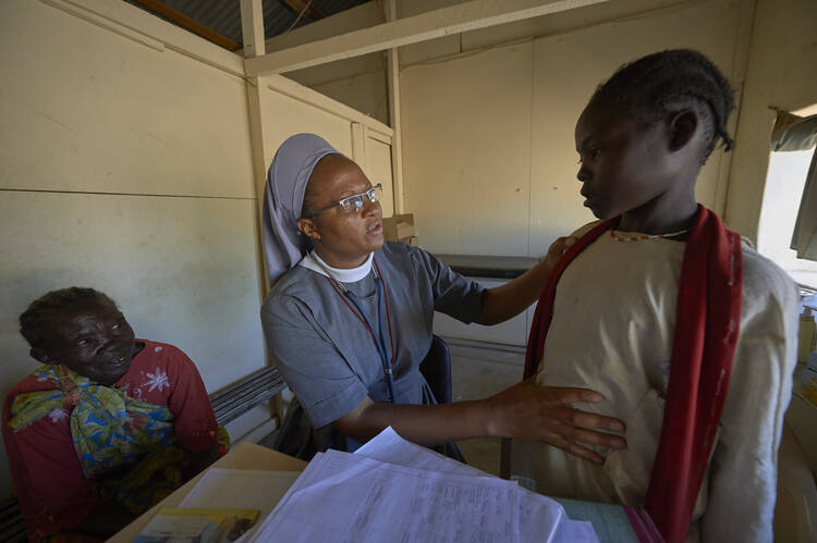 Precious Blood Sister Catherine Tukay examines a young patient in the Catholic clinic in Kauda, a village in the Nuba Mountains of Sudan, April 30. (CNS photo/Paul Jeffrey) 